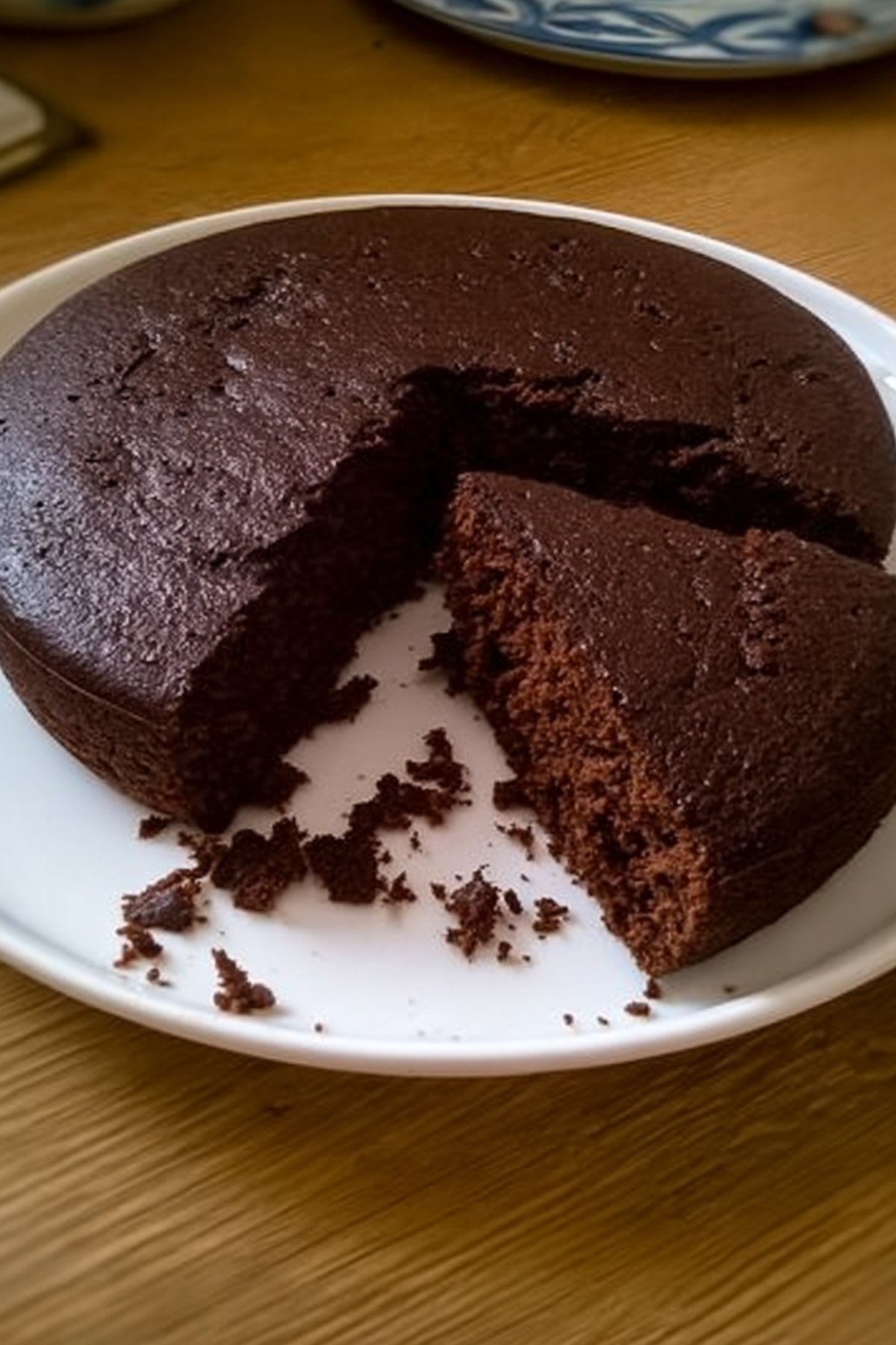 Photo d’un gâteau au yaourt et cacao en poudre moelleux avec une part découpée sur une assiette blanche.