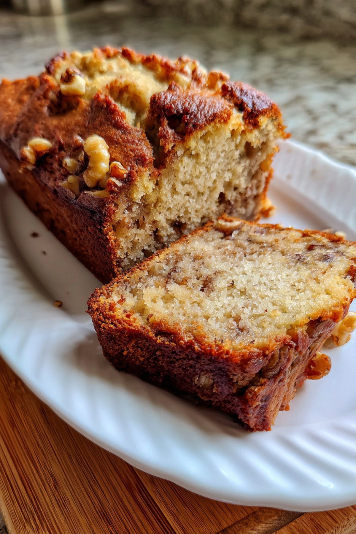 Cake banane et noix sans sucre, moelleux et doré, tranché sur une assiette blanche.