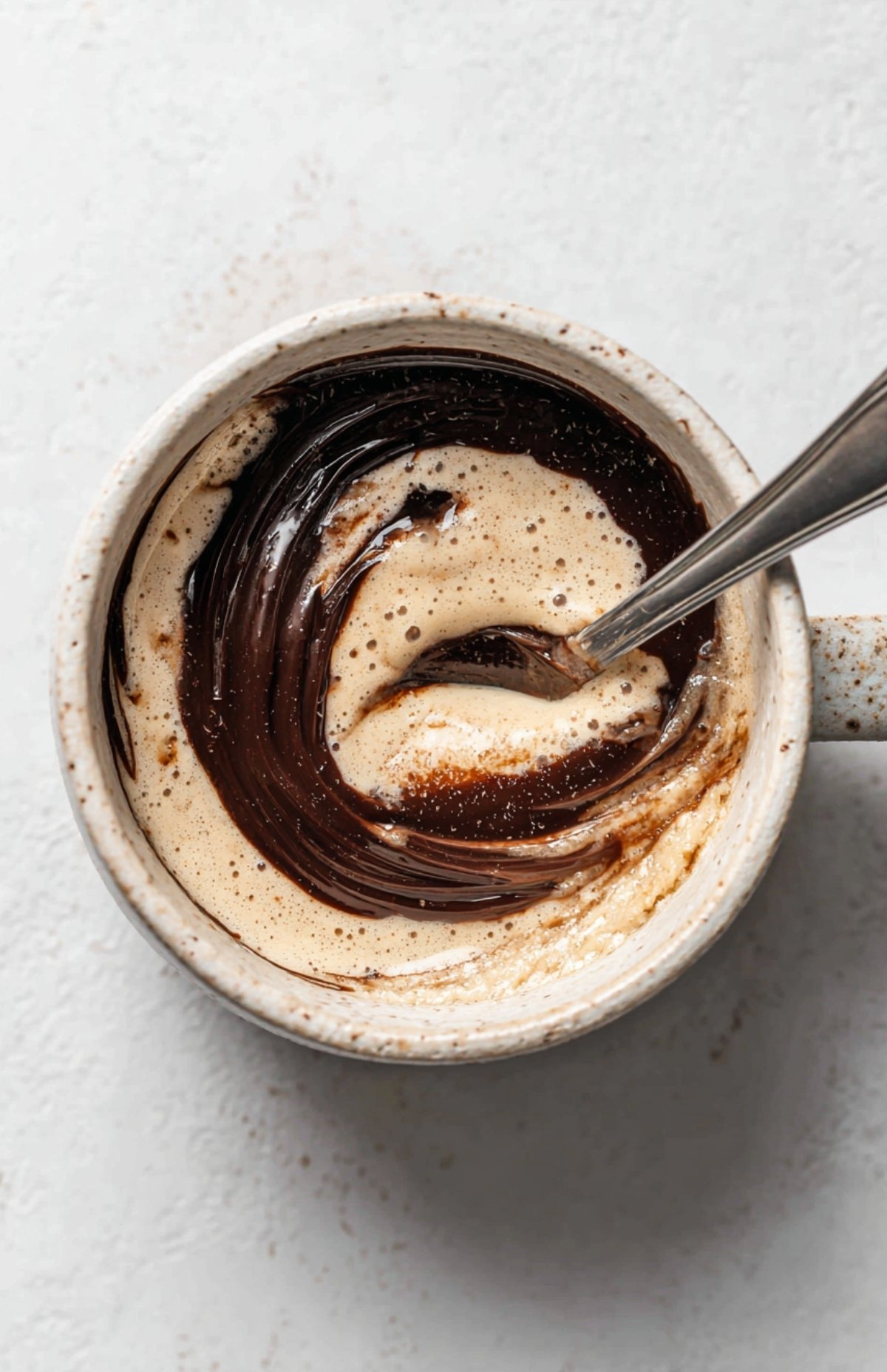 Mélange de Nutella avec la pâte dans un mug pour mug cake sans œuf prêt à cuire