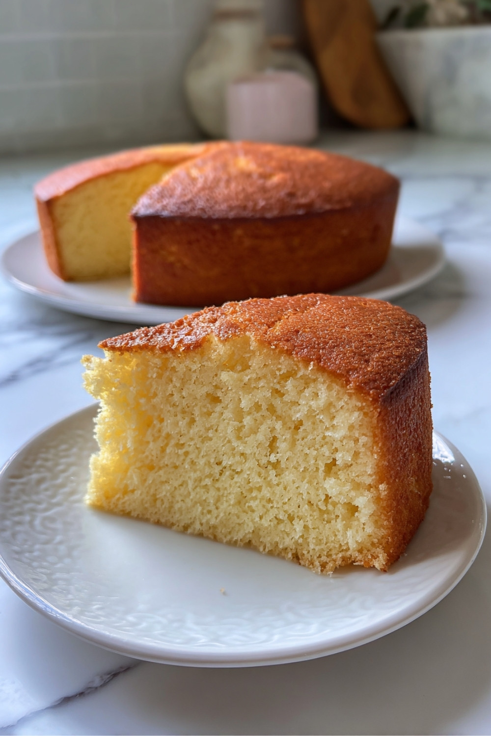 Tranche de gâteau au yaourt sans oeuf légère et aérée servie sur une assiette blanche