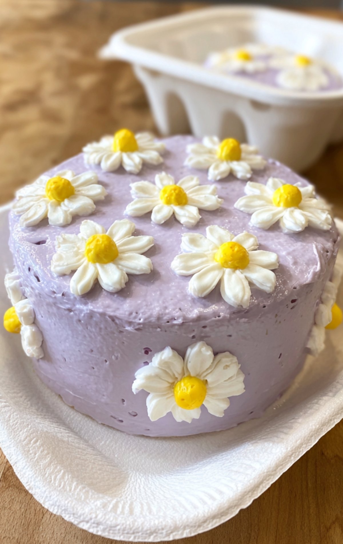 Bento cake maison violet décoré de marguerites en crème, prêt à mettre dans une boîte à bento.