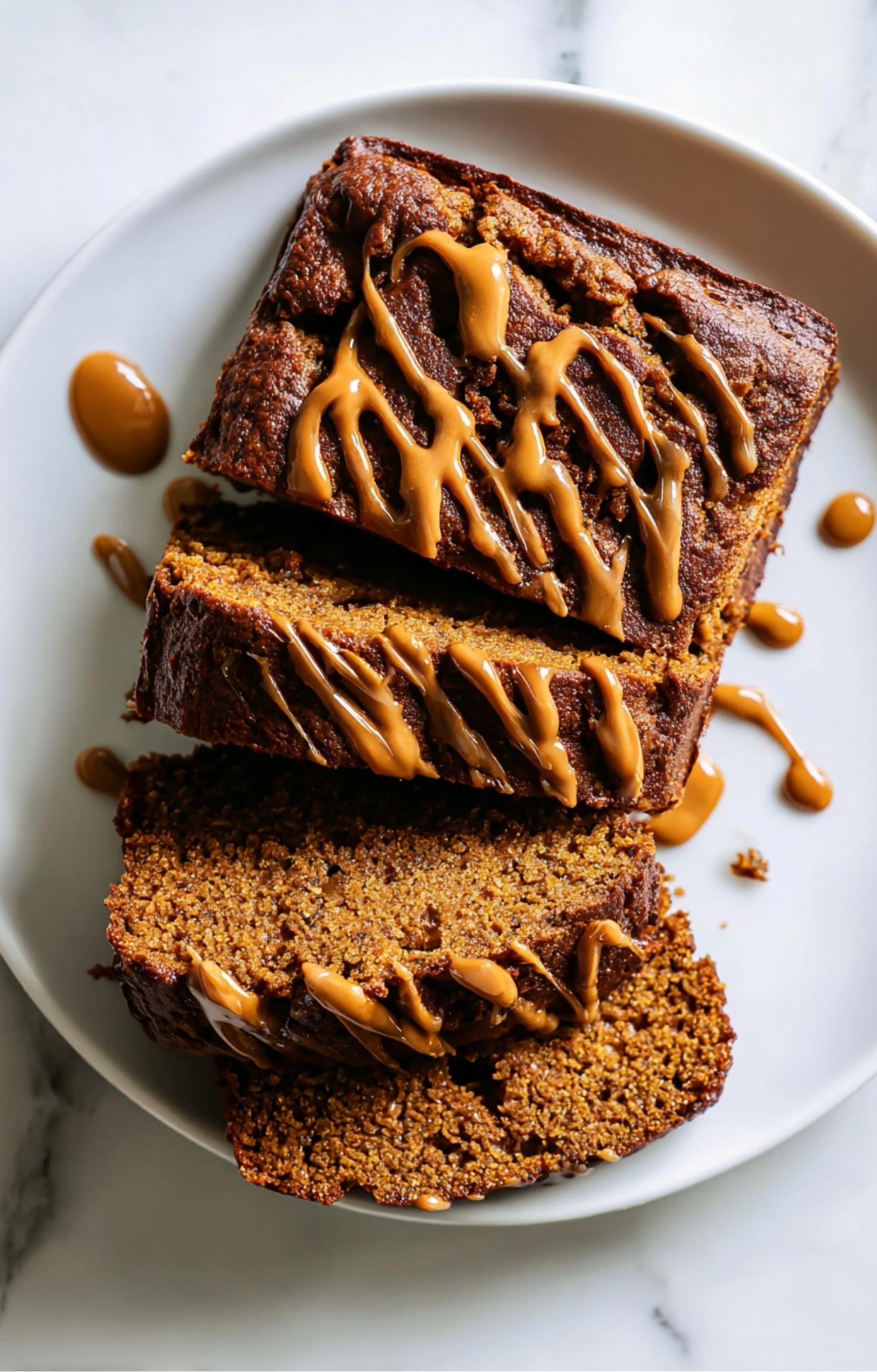 Tranches de cake au chocolat sans sucre ajouté et riche en protéines, servies sur une assiette blanche avec coulis au caramel naturel.