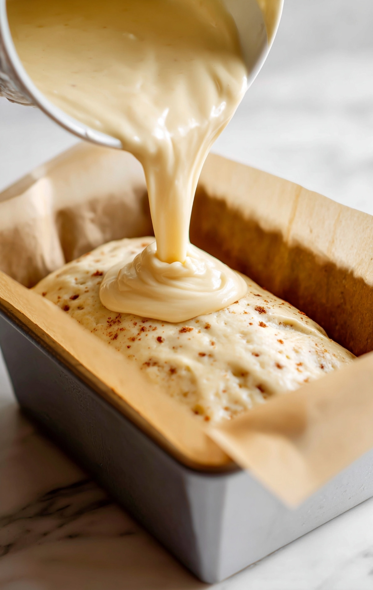 Versement d'une pâte lisse dans un moule à cake tapissé de papier cuisson