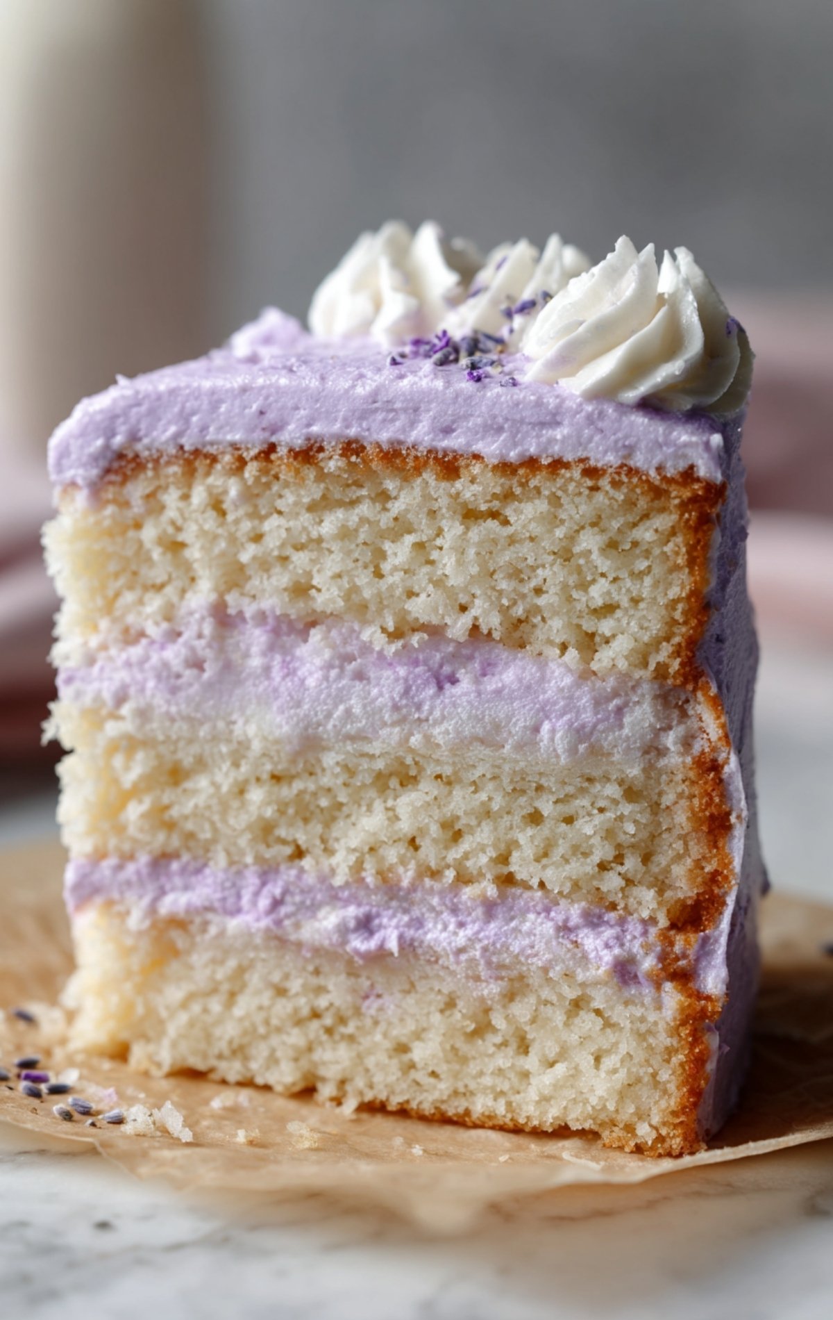 Part de bento cake montrant l'intérieur à 3 couches avec crème violette et génoise moelleuse.