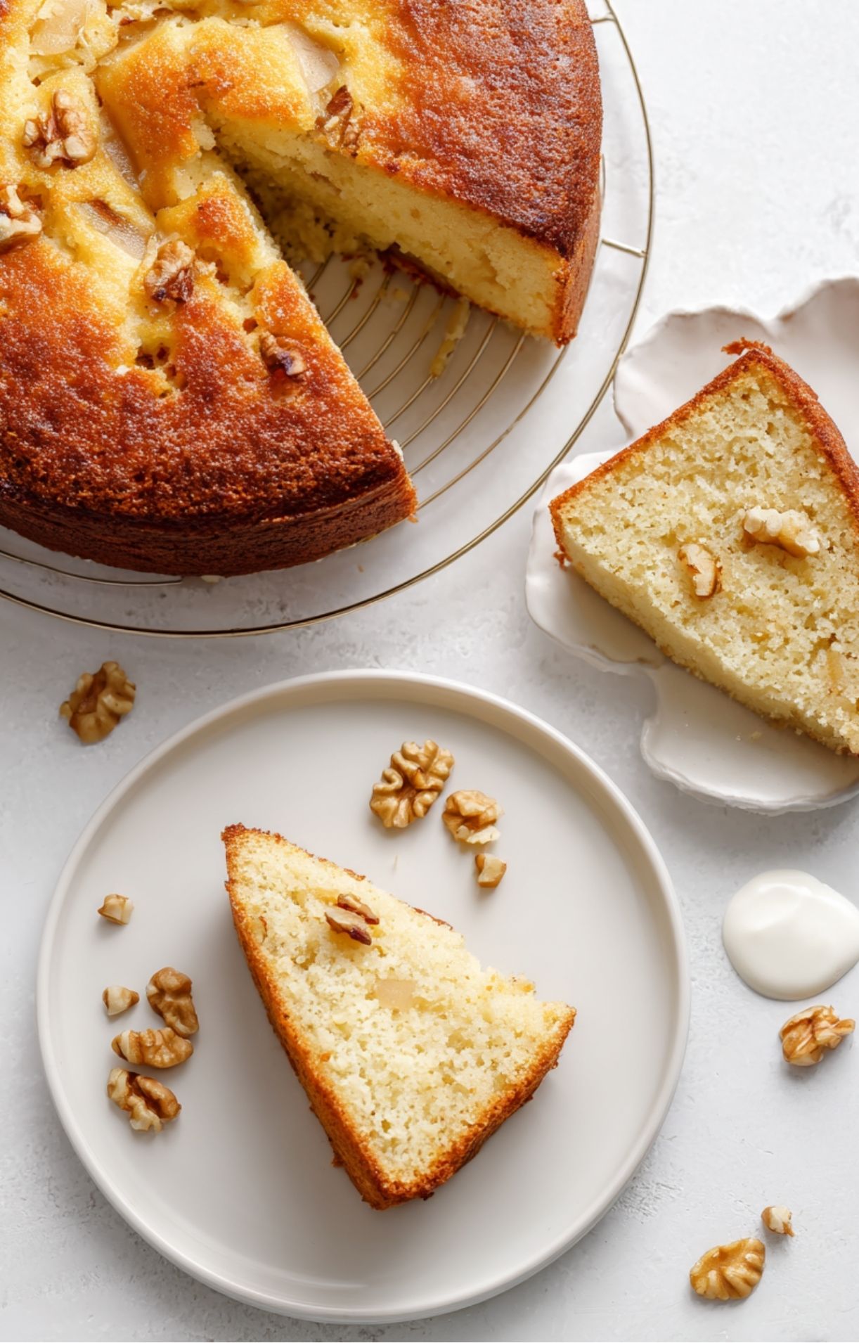 Gâteau entier doré sur une grille, une part découpée et la mie humide visible, noix sur le dessus