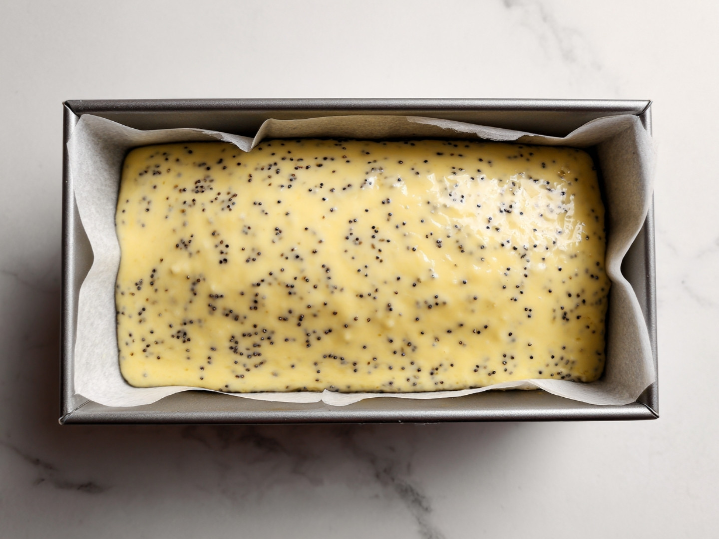 Pâte à gâteau citron pavot versée dans un moule à cake chemisé.