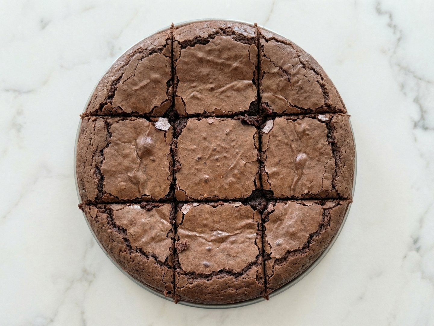 Brownie au chocolat cuit et découpé en carrés réguliers dans un moule rond