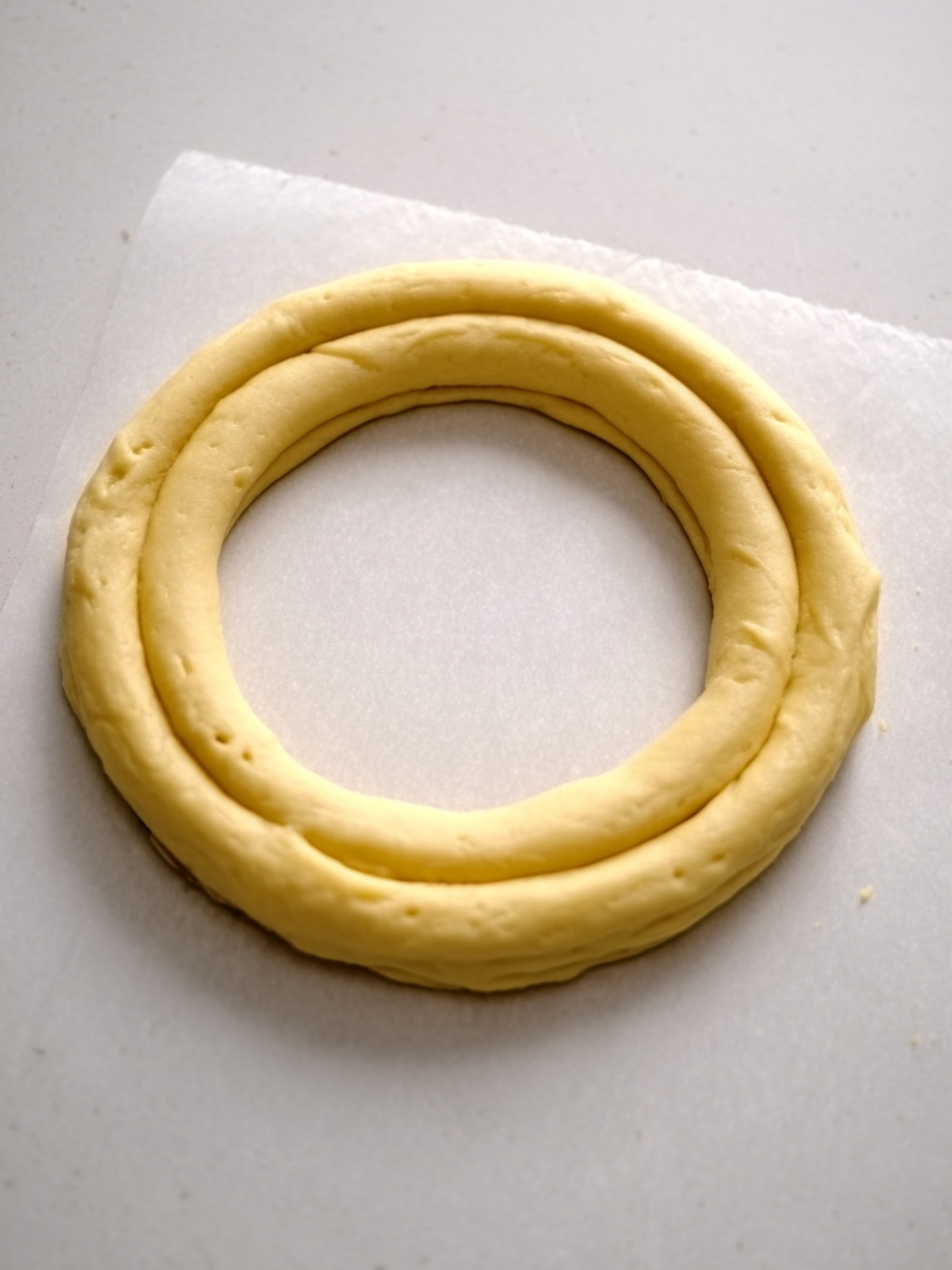 Formation de la couronne de pâte à choux crue sur une plaque de pâtisserie.