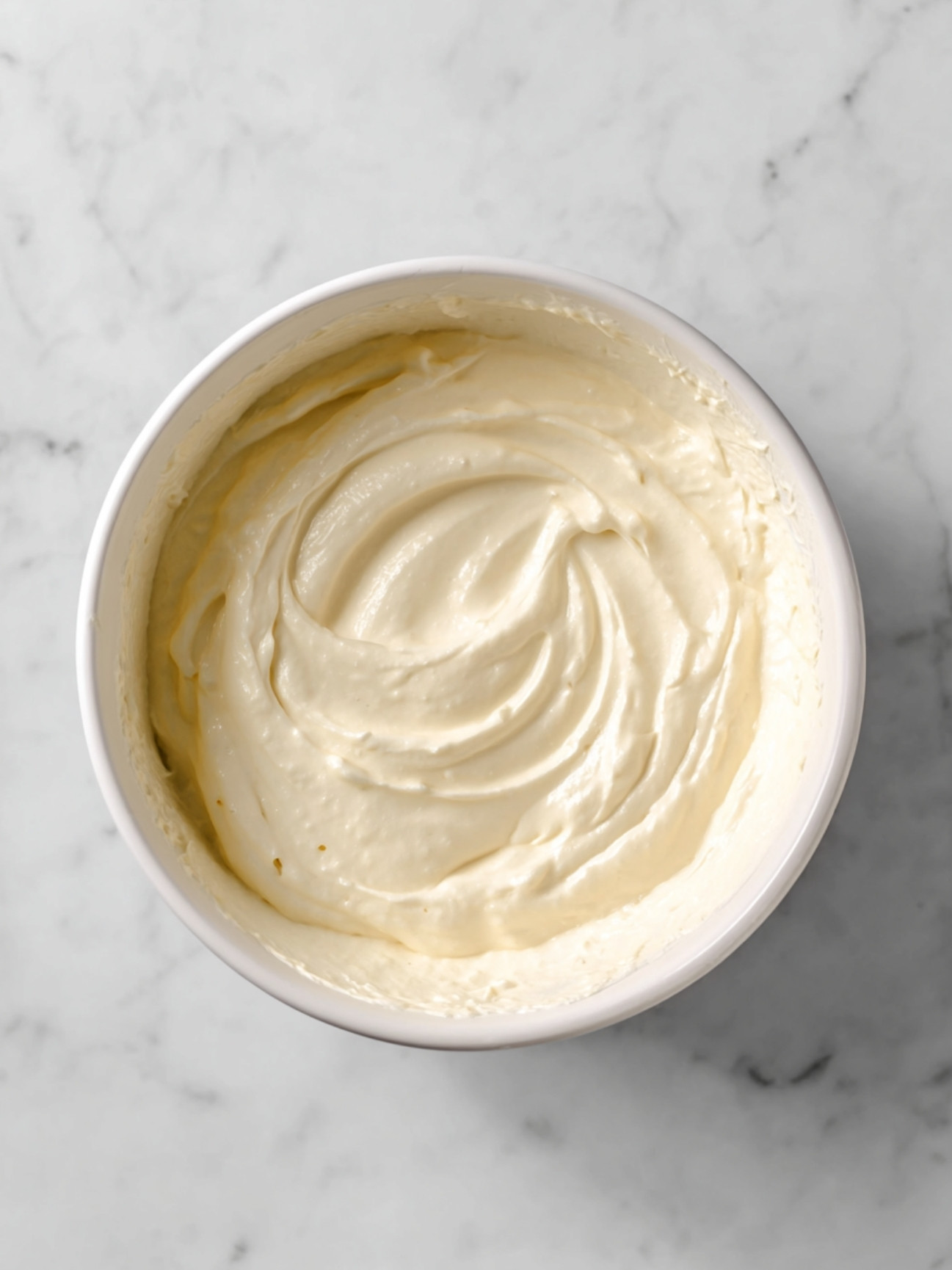 Mélange lisse et onctueux de mascarpone et sucre glace prêt pour l'incorporation.