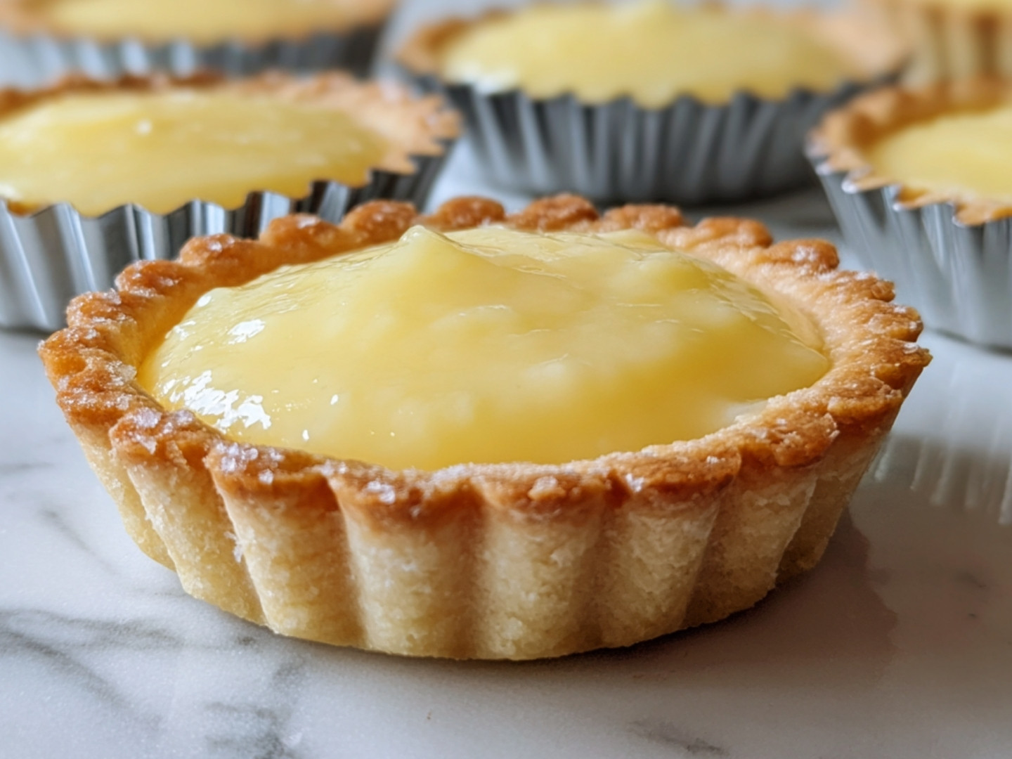 Tartelettes individuelles sorties du four avec une garniture au citron brillante.