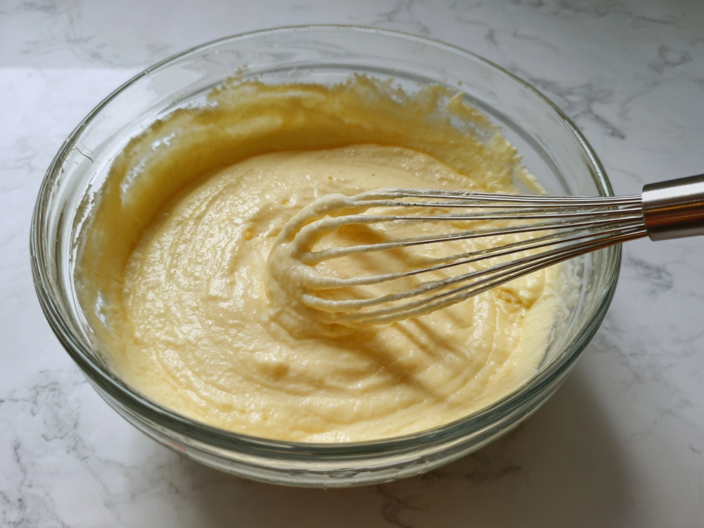 Mélange d'œufs et de sucre blanchi au fouet dans un saladier.