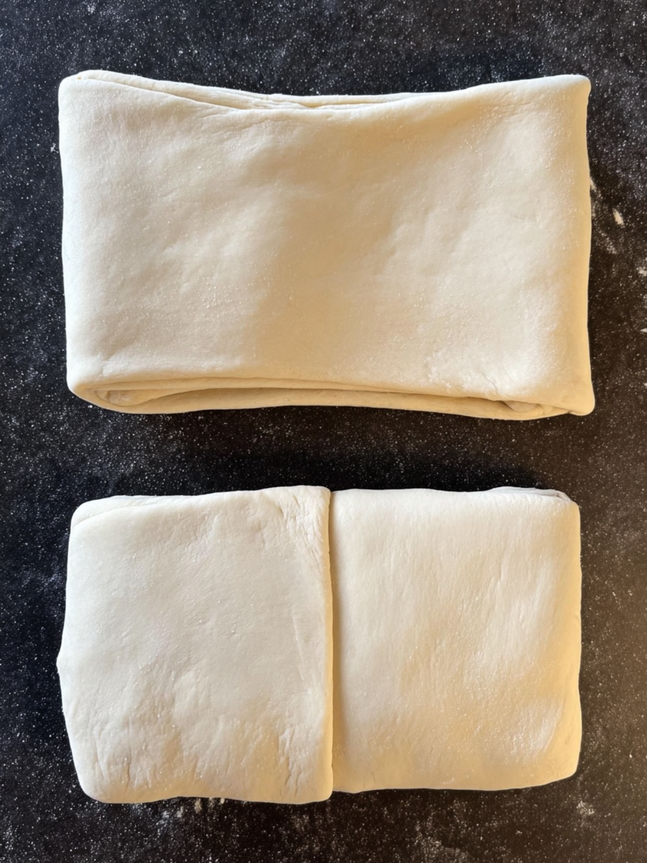 Pâte feuilletée levée pliée en tour portefeuille sur un plan de travail noir.