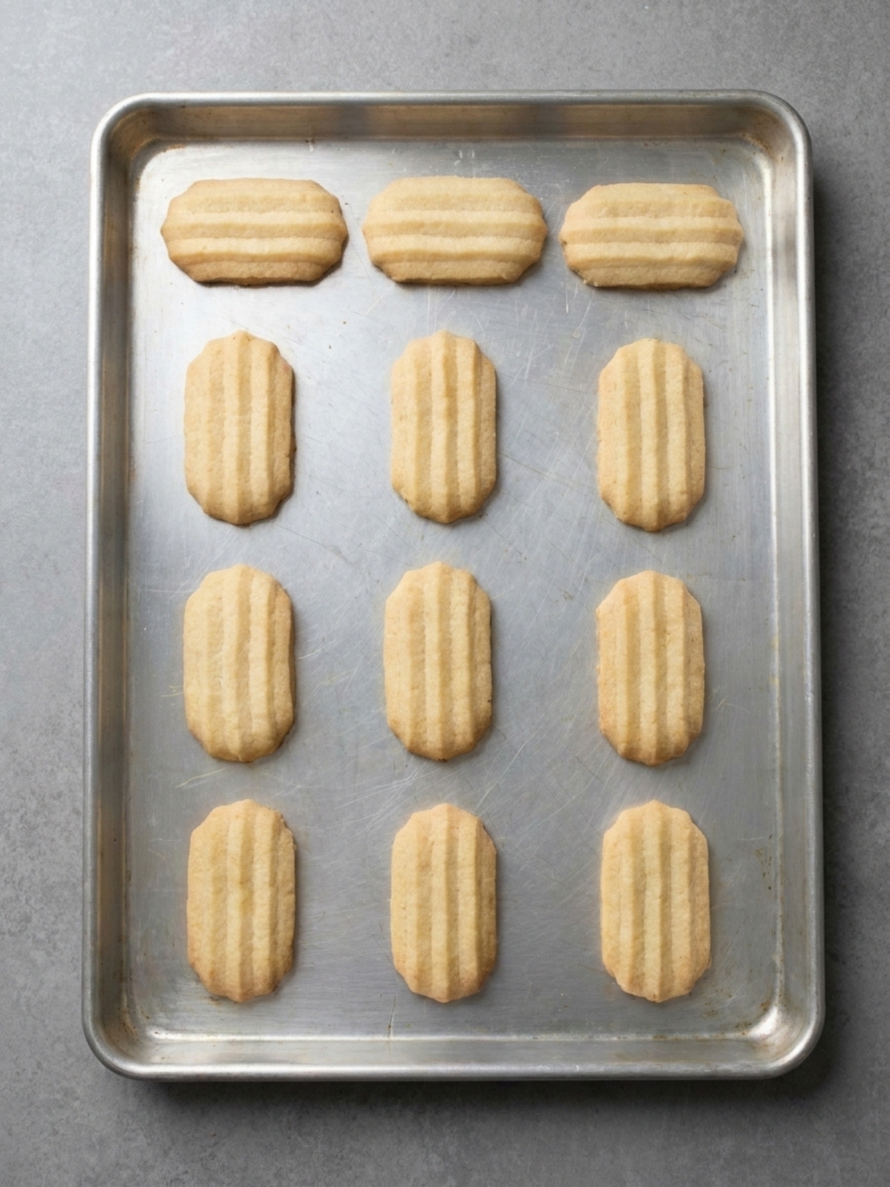 Biscuits spritz gateau alsacien cuits et dorés alignés sur une plaque de cuisson.