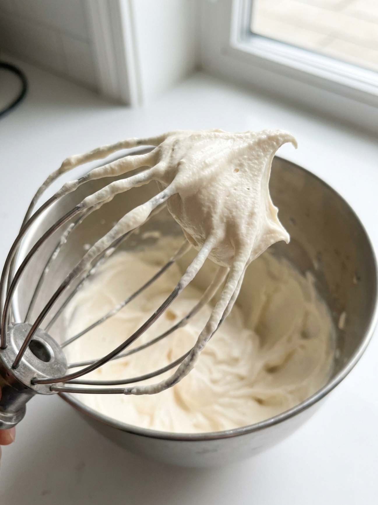 Gros plan sur un fouet de pâtissier avec une crème épaisse pour gateau mascarpone et speculoos.