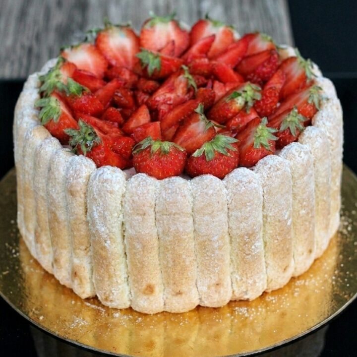Gâteau charlotte aux fraises entier posé sur un support doré festif charlotte aux fraises recette