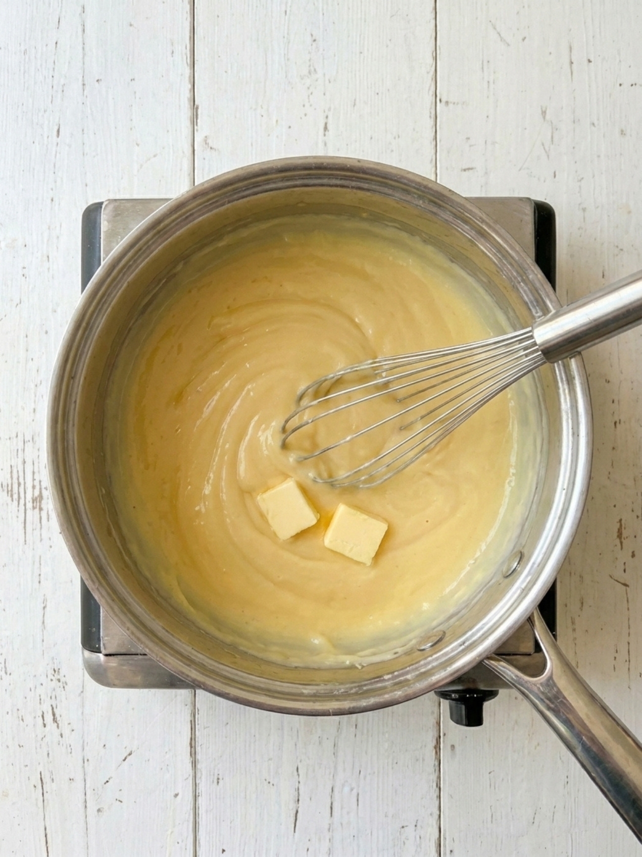 Fouet mélangeant du beurre dans une crème pâtissière pour tarte aux fraises jaune et lisse.