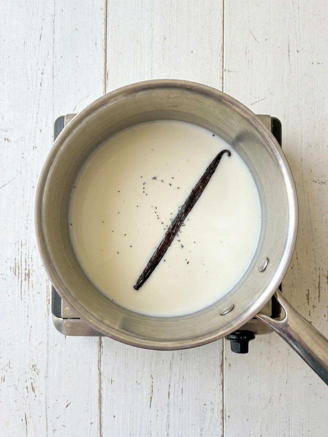 Gousse de vanille infusant dans du lait pour crème pâtissière pour tarte aux fraises.