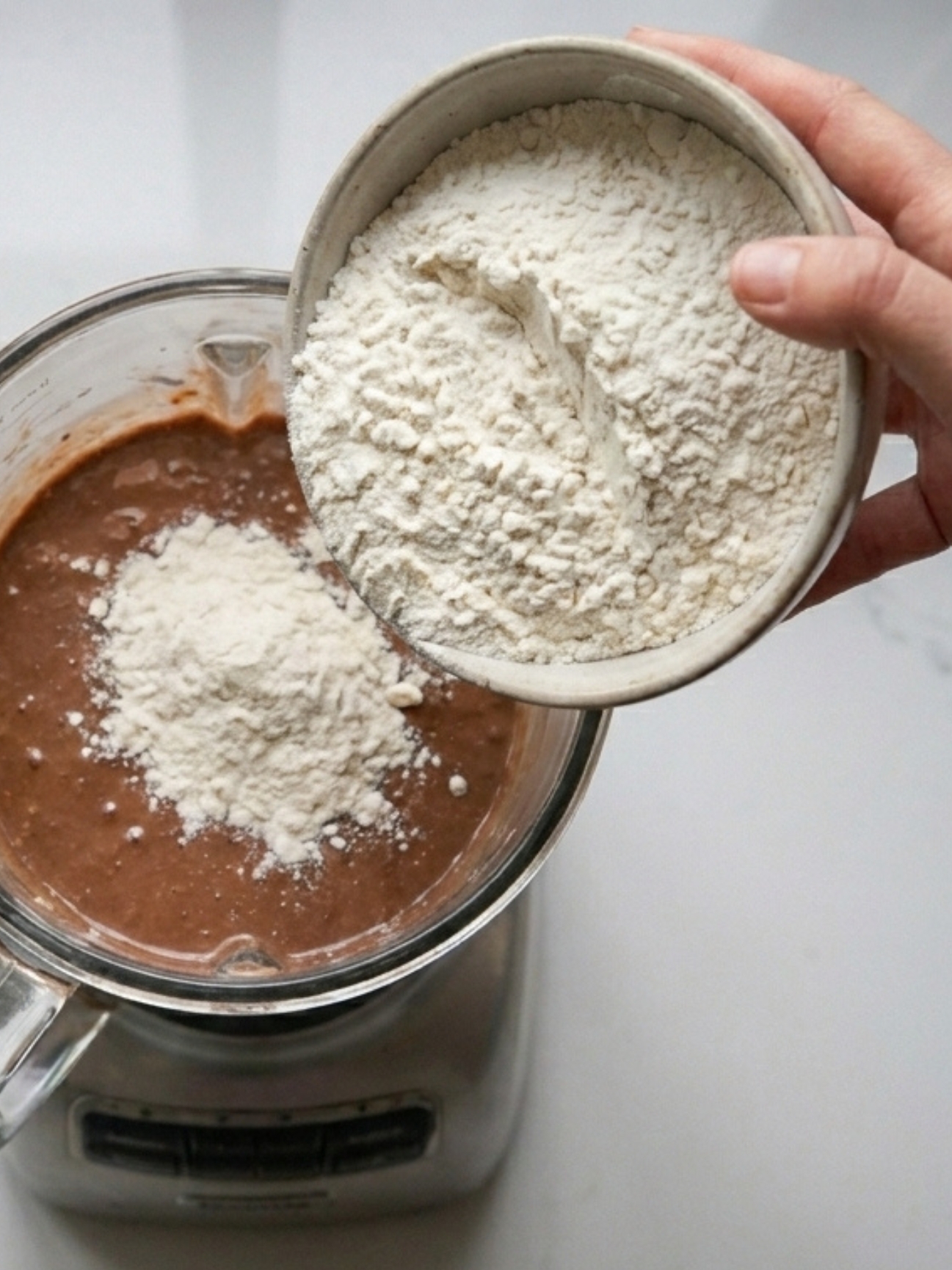 Ajout d'un bol de farine dans le mélangeur pour le gâteau banane chocolat.