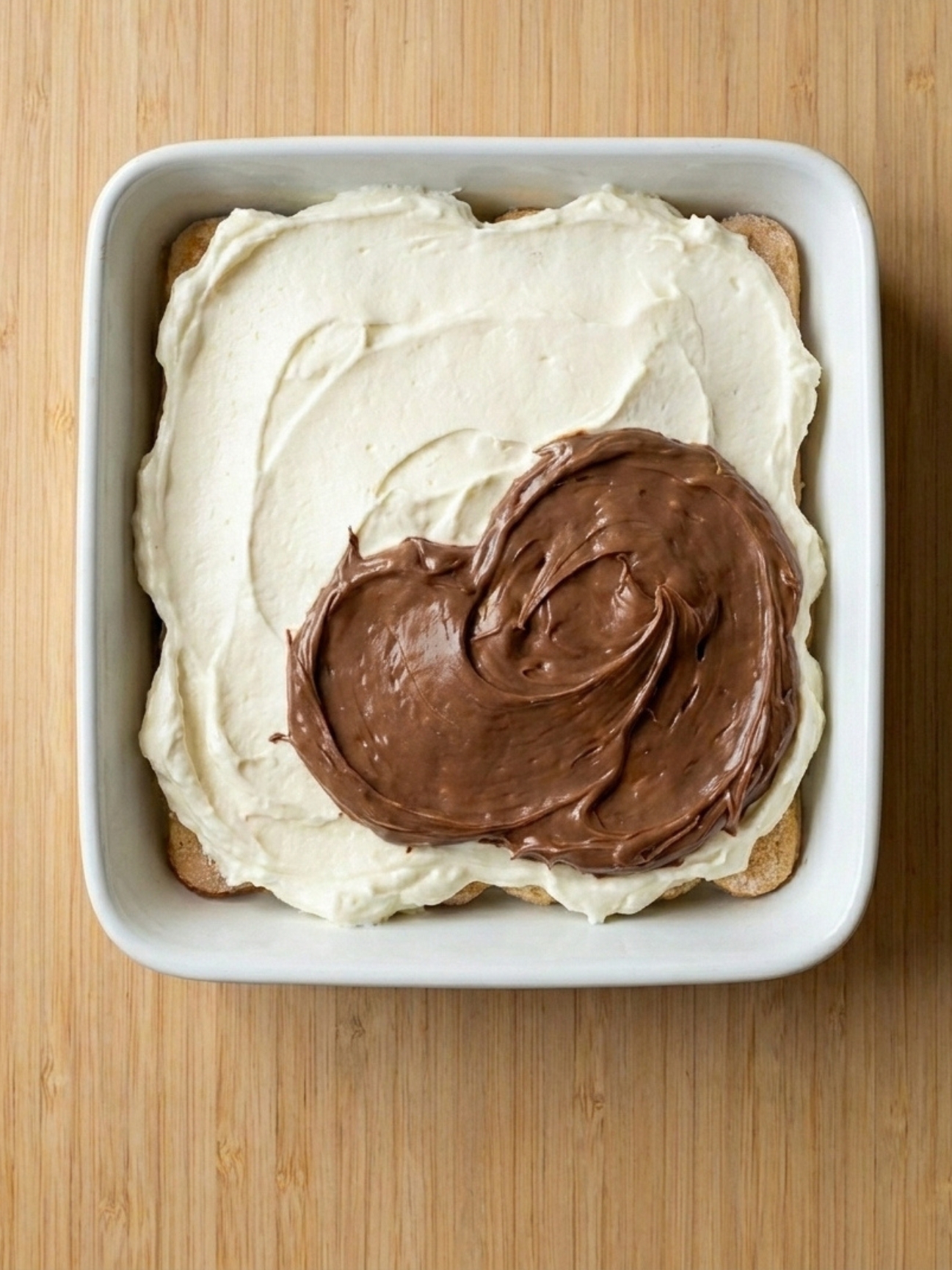 Biscuits cuillères imbibés alignés dans un plat pour gâteau Kinder Bueno White.