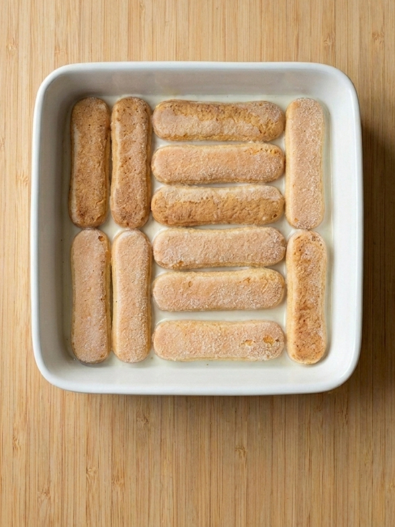 Étape de montage d'un gâteau Kinder Bueno White avec de la crème et du chocolat.