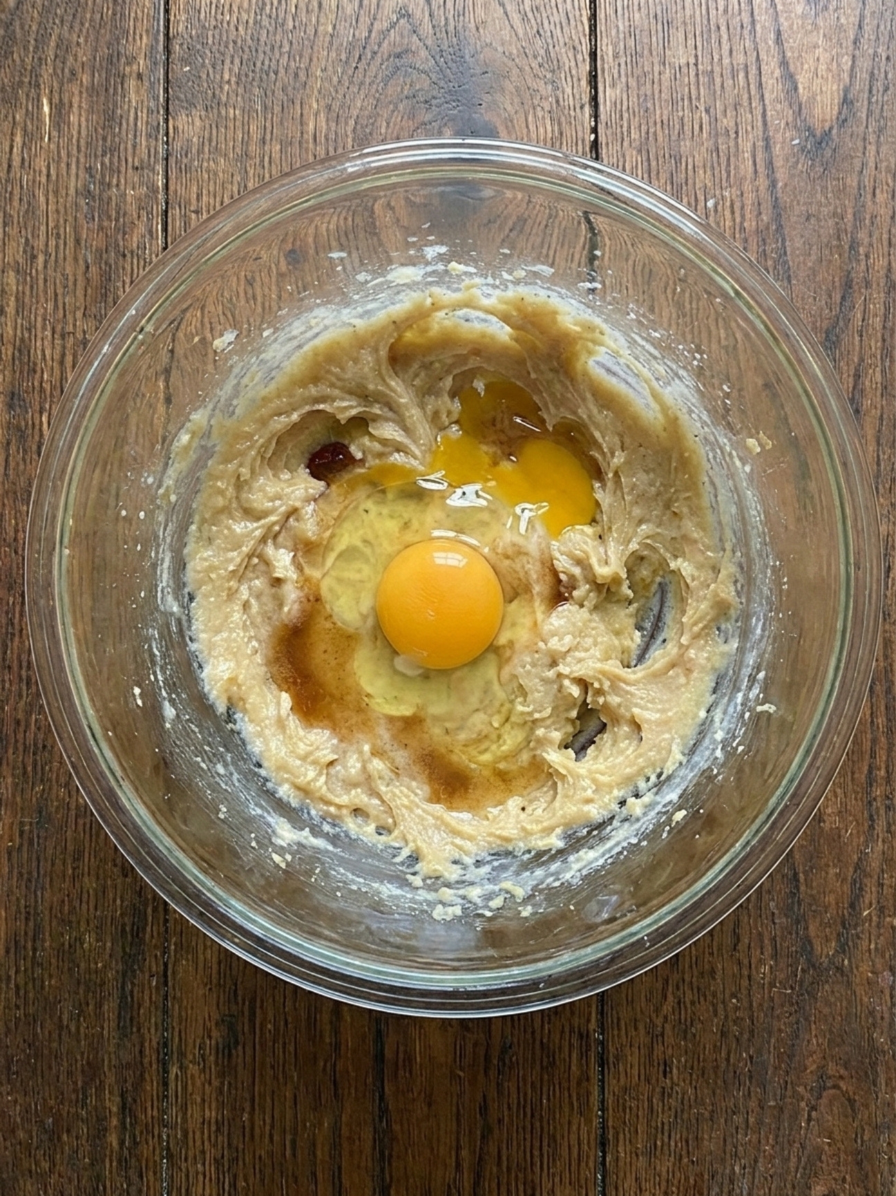 Ajout d'un œuf entier au mélange liquide pour préparer la pâte du granola biscuit.