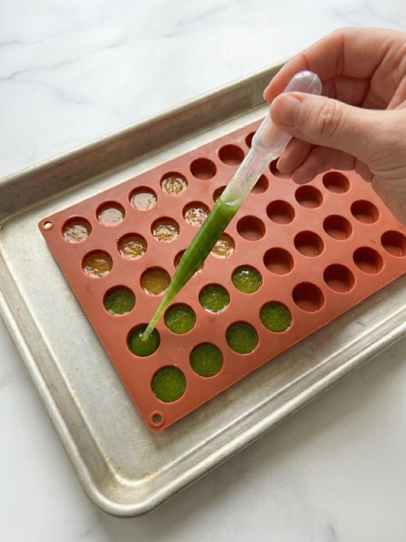 Utilisation d'une pipette pour verser la recette bonbon gelatine maison dans un moule.