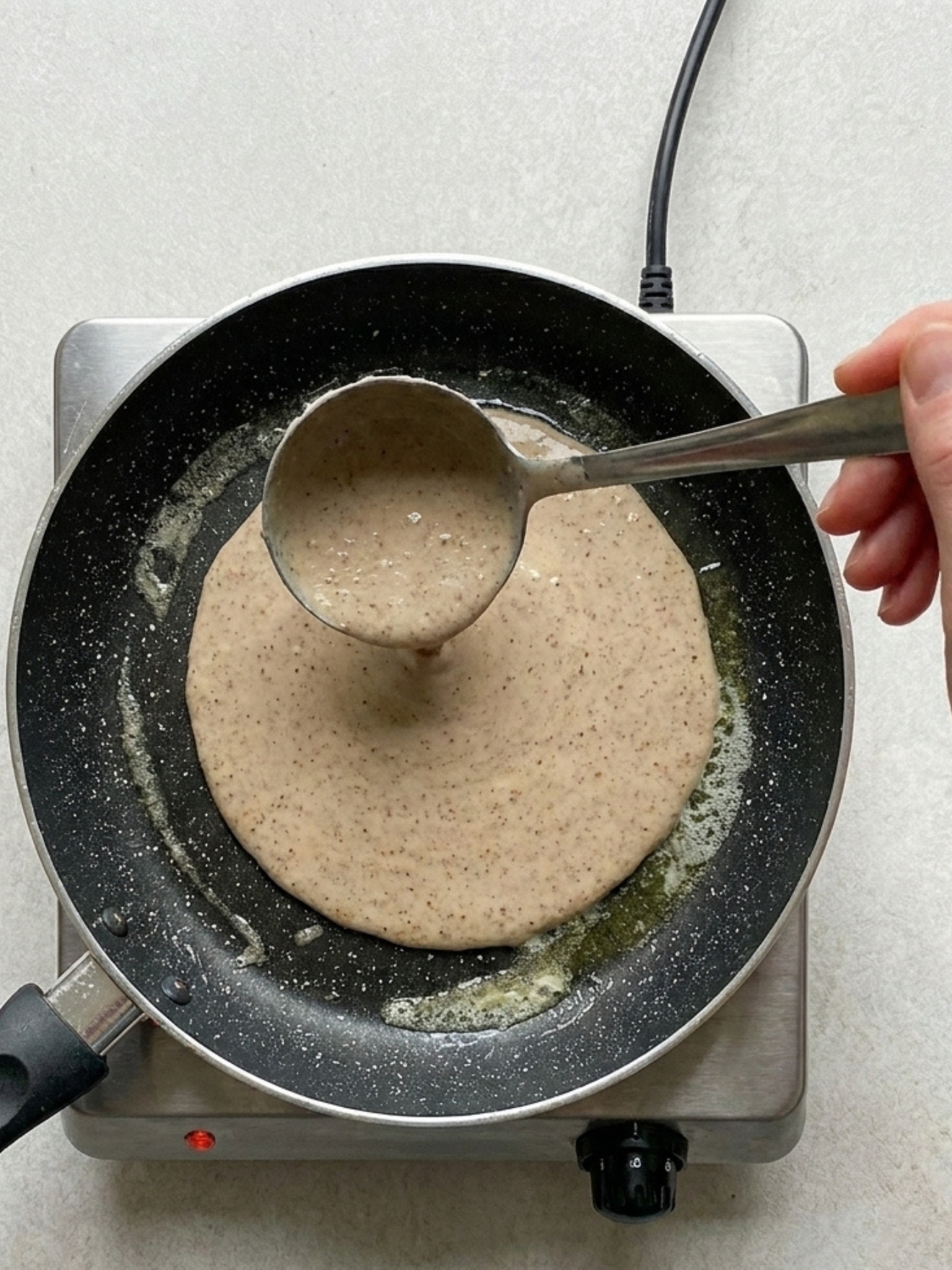 Louche versant de la pâte dans une poêle pour la recette des galettes bretonnes au sarrasin.
