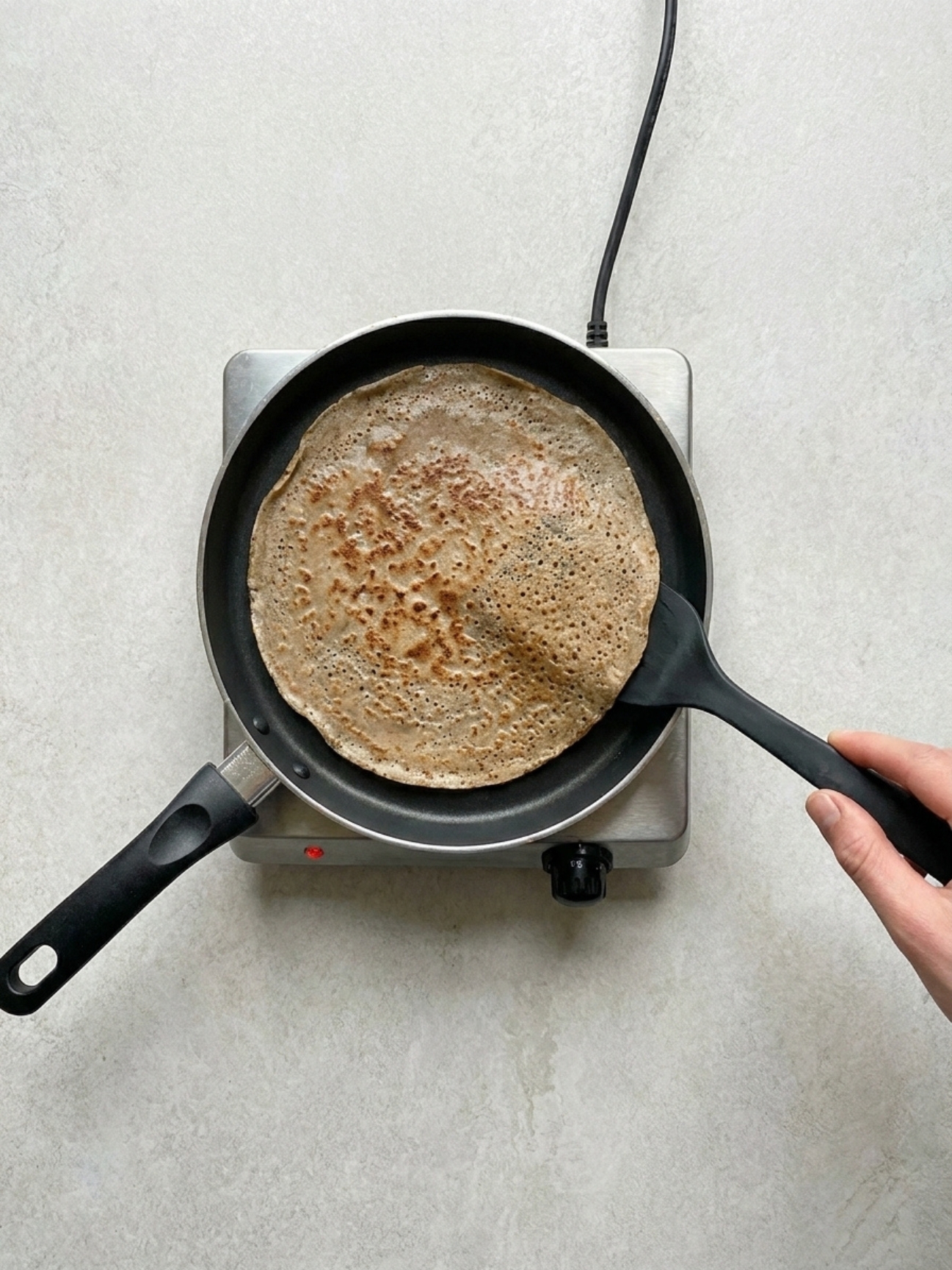 Spatule retournant une crêpe dorée pour la recette des galettes bretonnes au sarrasin au blé noir.