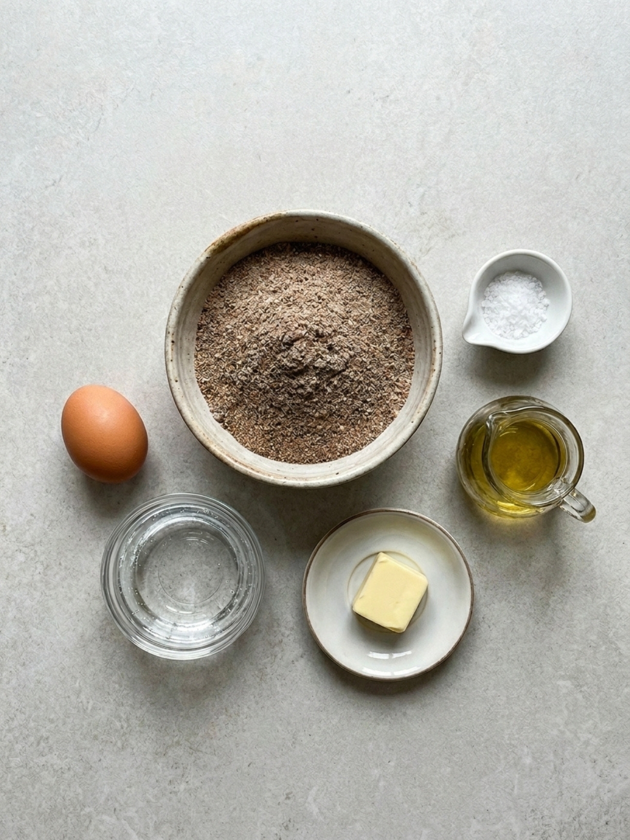 Ingrédients bruts sur table grise pour la recette des galettes bretonnes au sarrasin au blé noir.