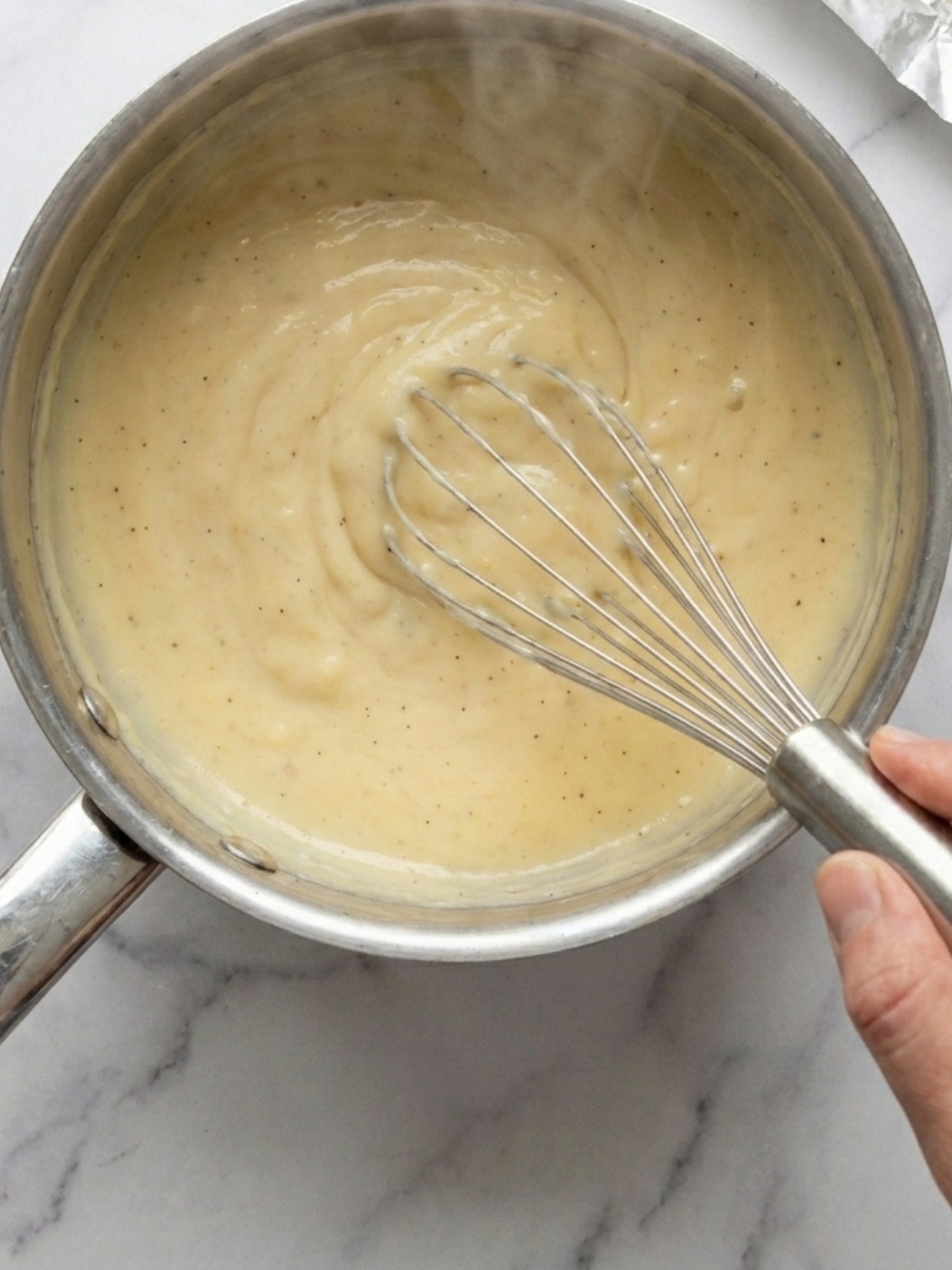 Crème à la vanille épaisse mélangée dans une casserole, recette mille feuille facile.