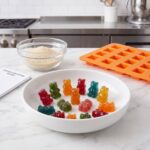 Bol blanc de bonbons gélifiés avec un moule en silicone orange et un bol de poudre.