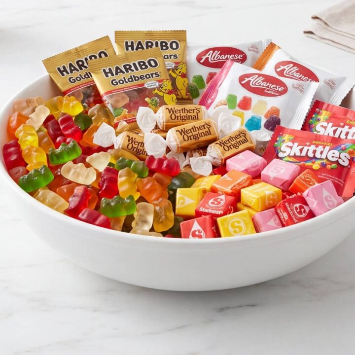 Assortiment de bonbons et sachets de différentes marques dans un grand bol blanc.