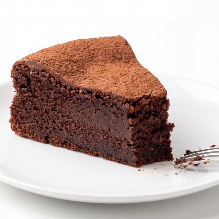 Part de gâteau au chocolat moelleux et dense sur une assiette avec une fourchette.