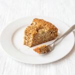 Part de gâteau coupe-faim aux flocons d'avoine, banane et skyr sur une assiette blanche avec une fourchette
