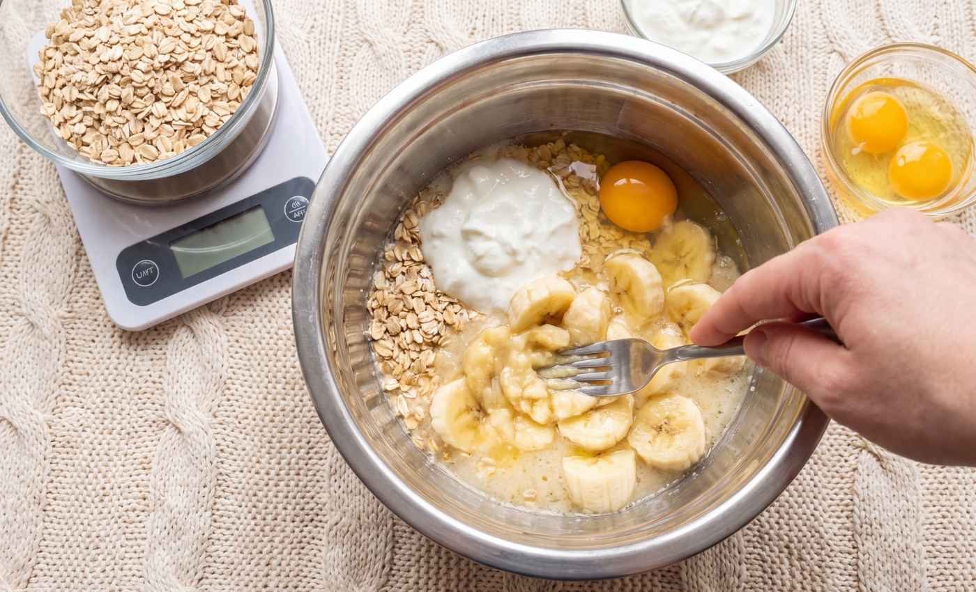 Préparation d'un gâteau coupe-faim aux flocons d'avoine, banane et skyr dans un saladier avec une fourchette