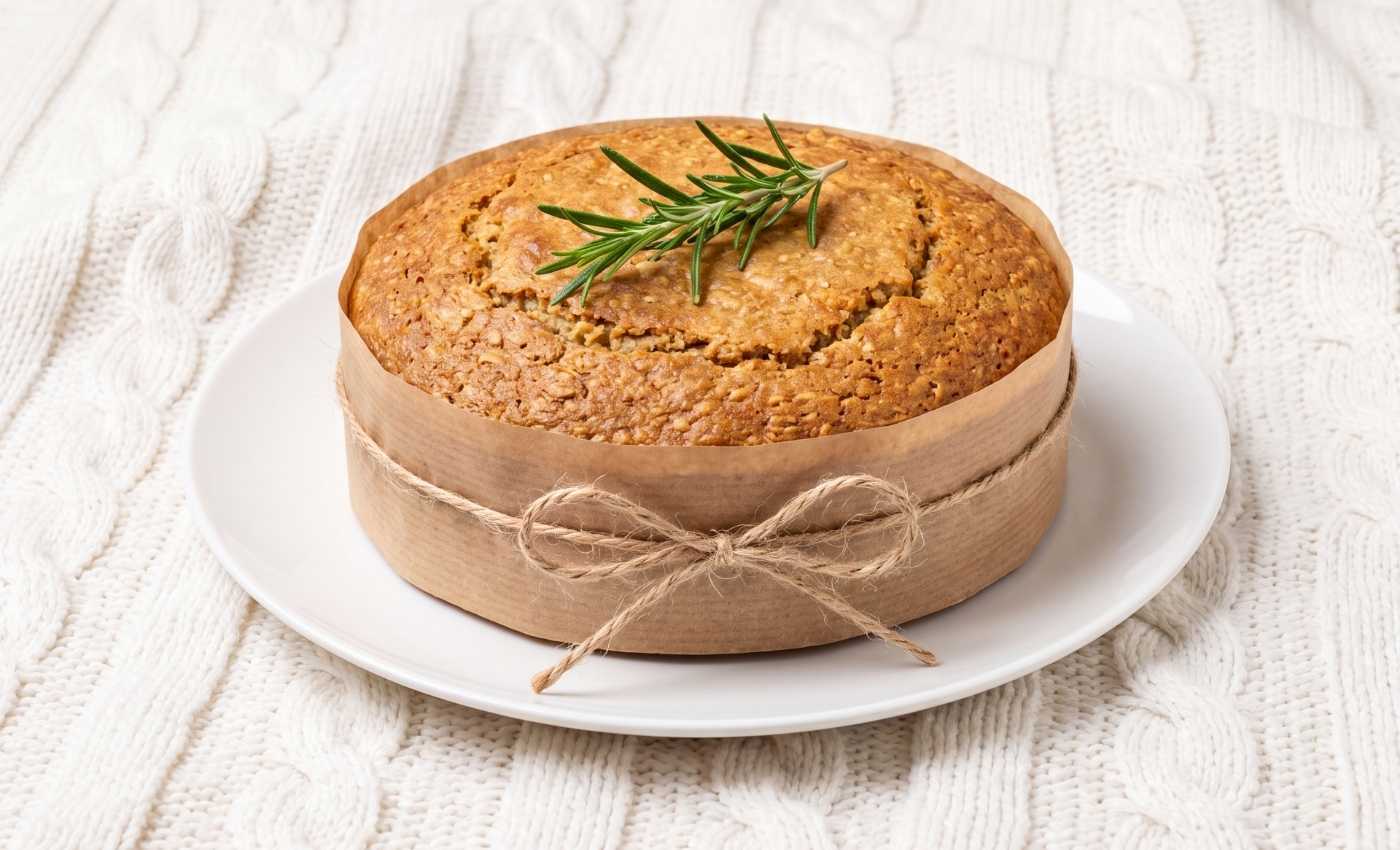 Gâteau coupe-faim à l'avoine, banane et skyr présenté comme un cadeau sur une assiette blanche avec un ruba