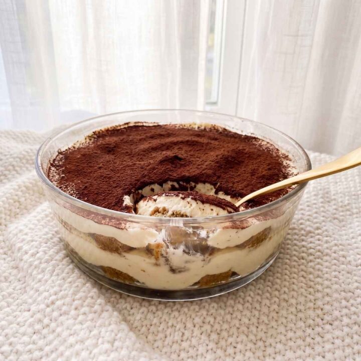 Tiramisu sans blanc d'œuf crémeux dans un plat rond, avec couches de biscuits au café, mascarpone et cacao.